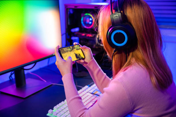 woman is playing video game without any lag via smartphone at home neon lights living room. 