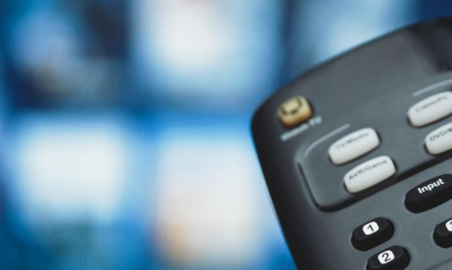 remote control in front of an out of focus tv