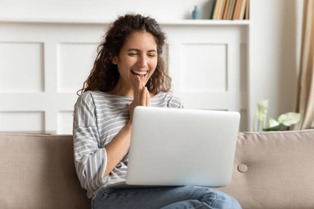 Overjoyed young woman looking at laptop screen, feeling excited about good high speed low cost internet